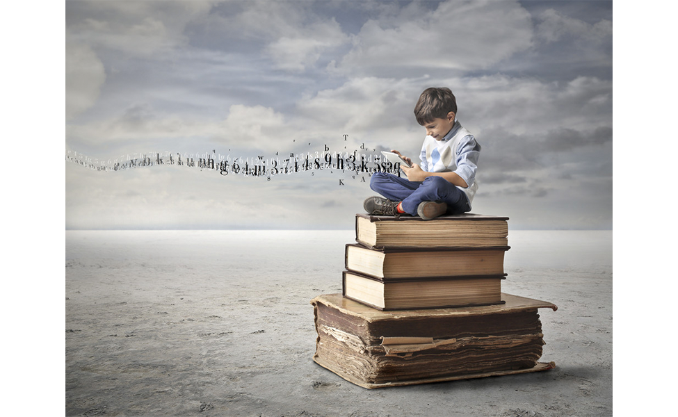 Boy sits on stack of books using tablet