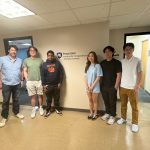 A group of six stand for a photo in front of a beige wall with a navy blue Penn State ICDS sign.