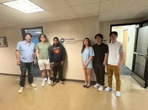 A group of six stand for a photo in front of a beige wall with a navy blue Penn State ICDS sign.